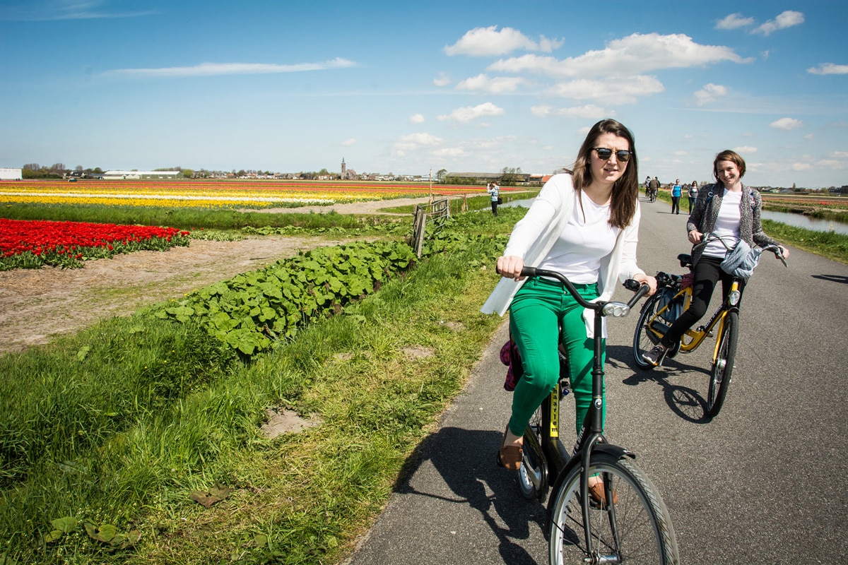 Two girld biking through tulips in the Netherlands