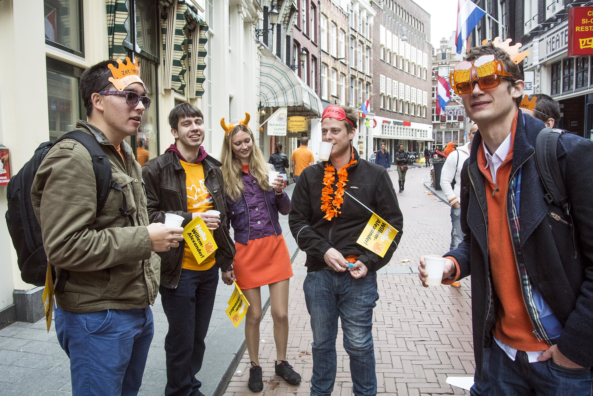 Several people drinking on the street while being dressed up for King's Day