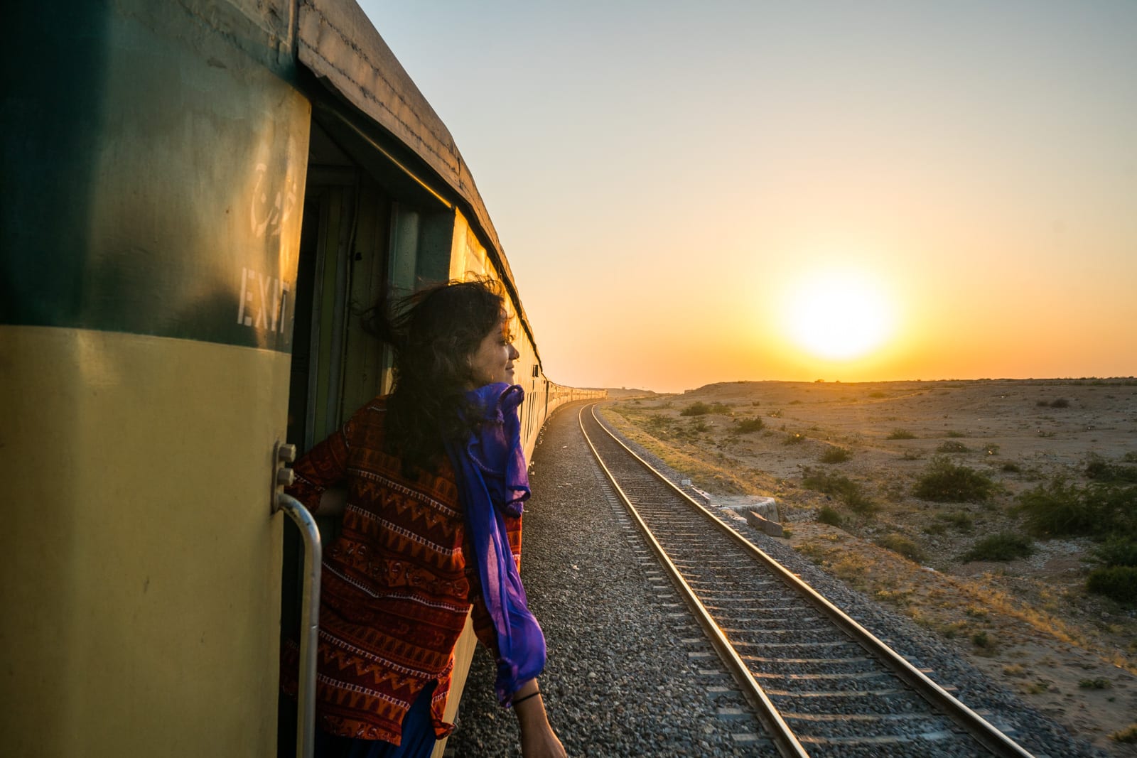 A girl hanging out the door of a moving train in Pakistan