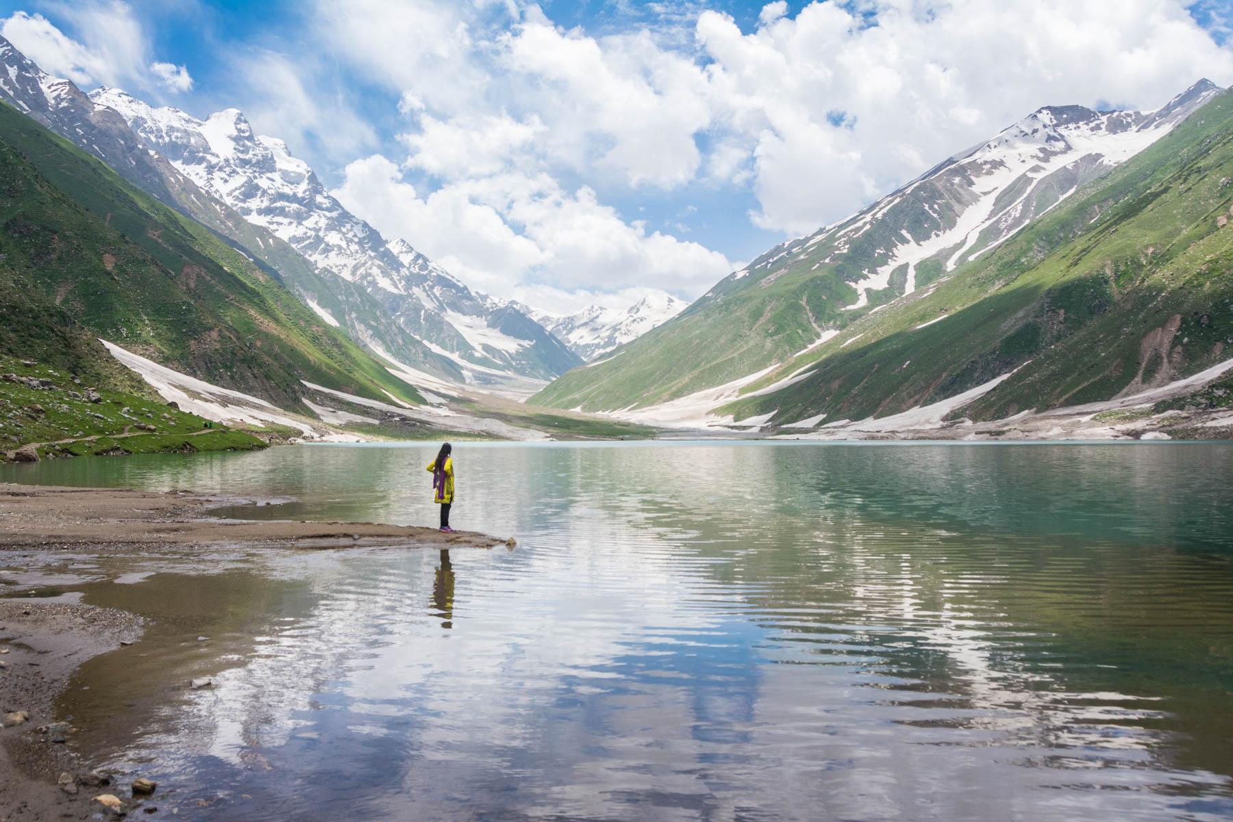 A solo female traveler standing near a lake in Pakistan