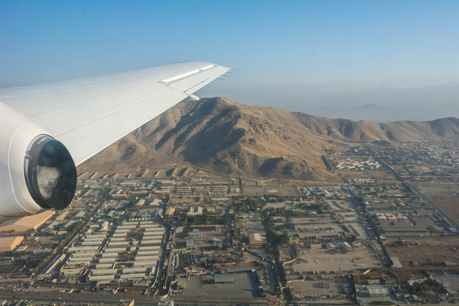 A plane flying over Kabul with views of the city