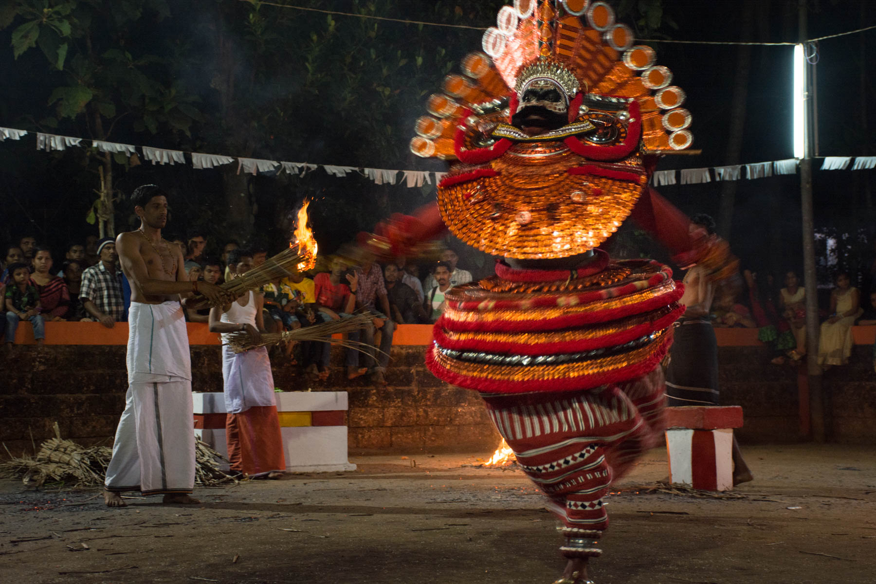 Spinning Theyyam dancer with a priest in the background