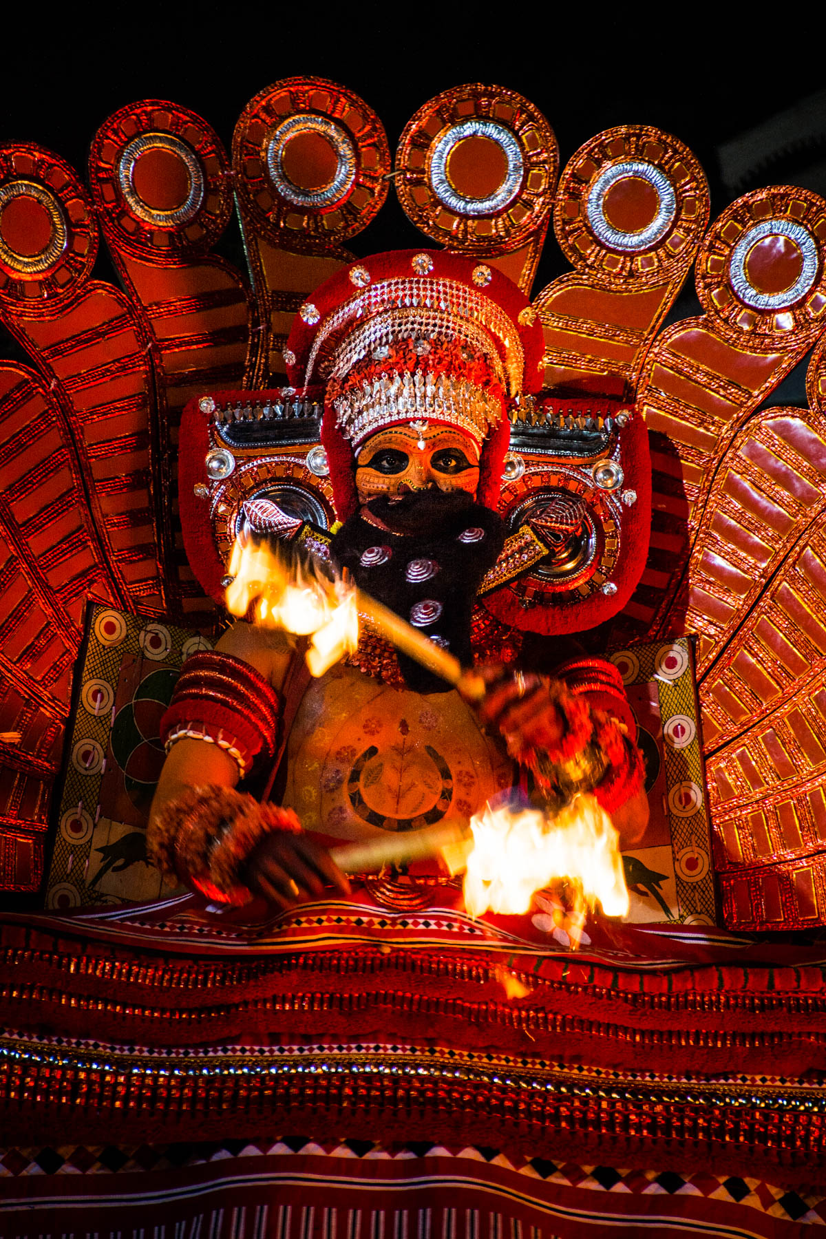 A close up shot of the Kutty Theyyam peformer playing with fire