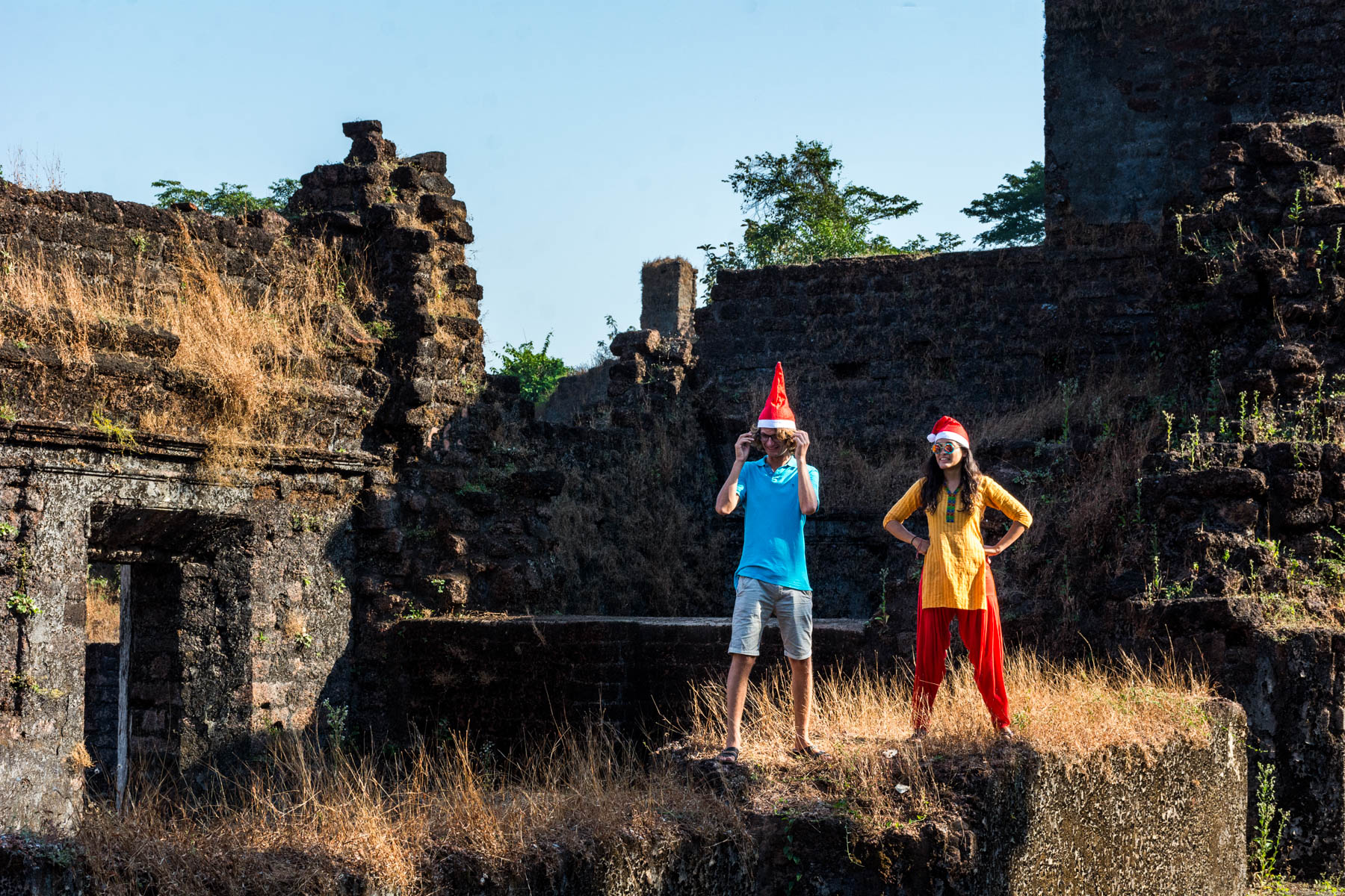 Two foreigners wearing Santa hats in church ruins