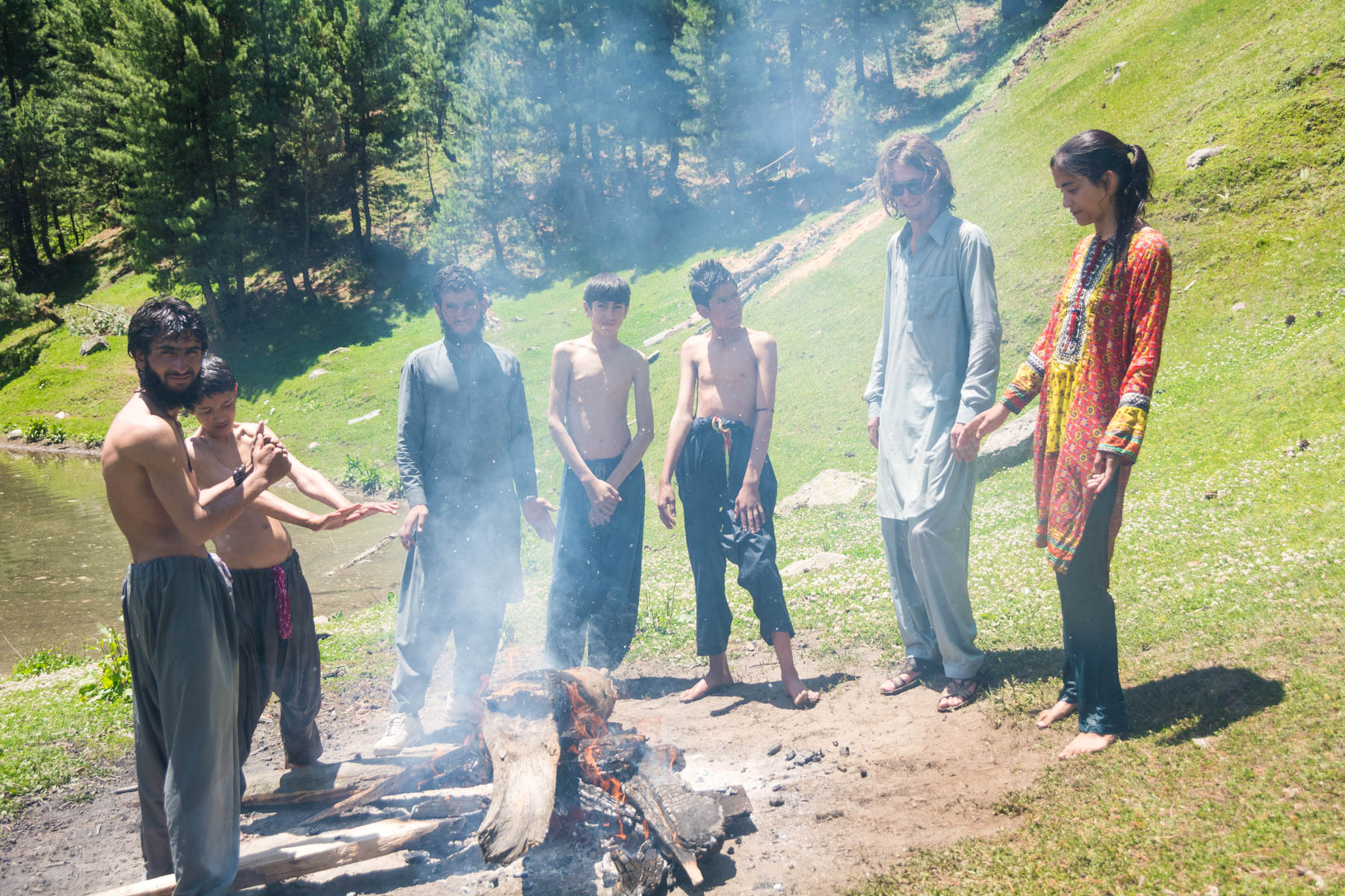 A group of men and a girl standing next to a camp fire in Pakistan