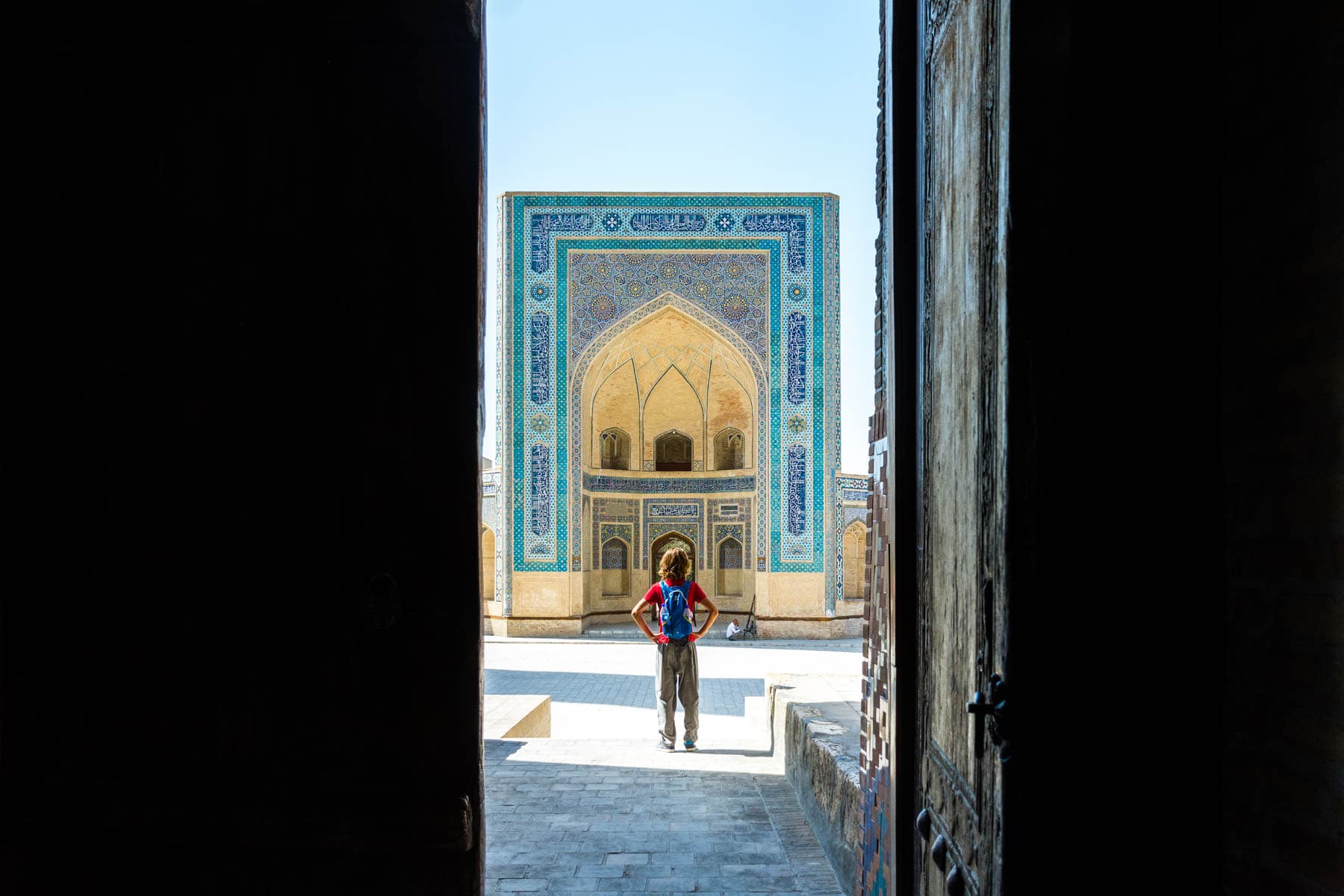 A boy Looking through doors to the Kaylan mosque in Bukhara