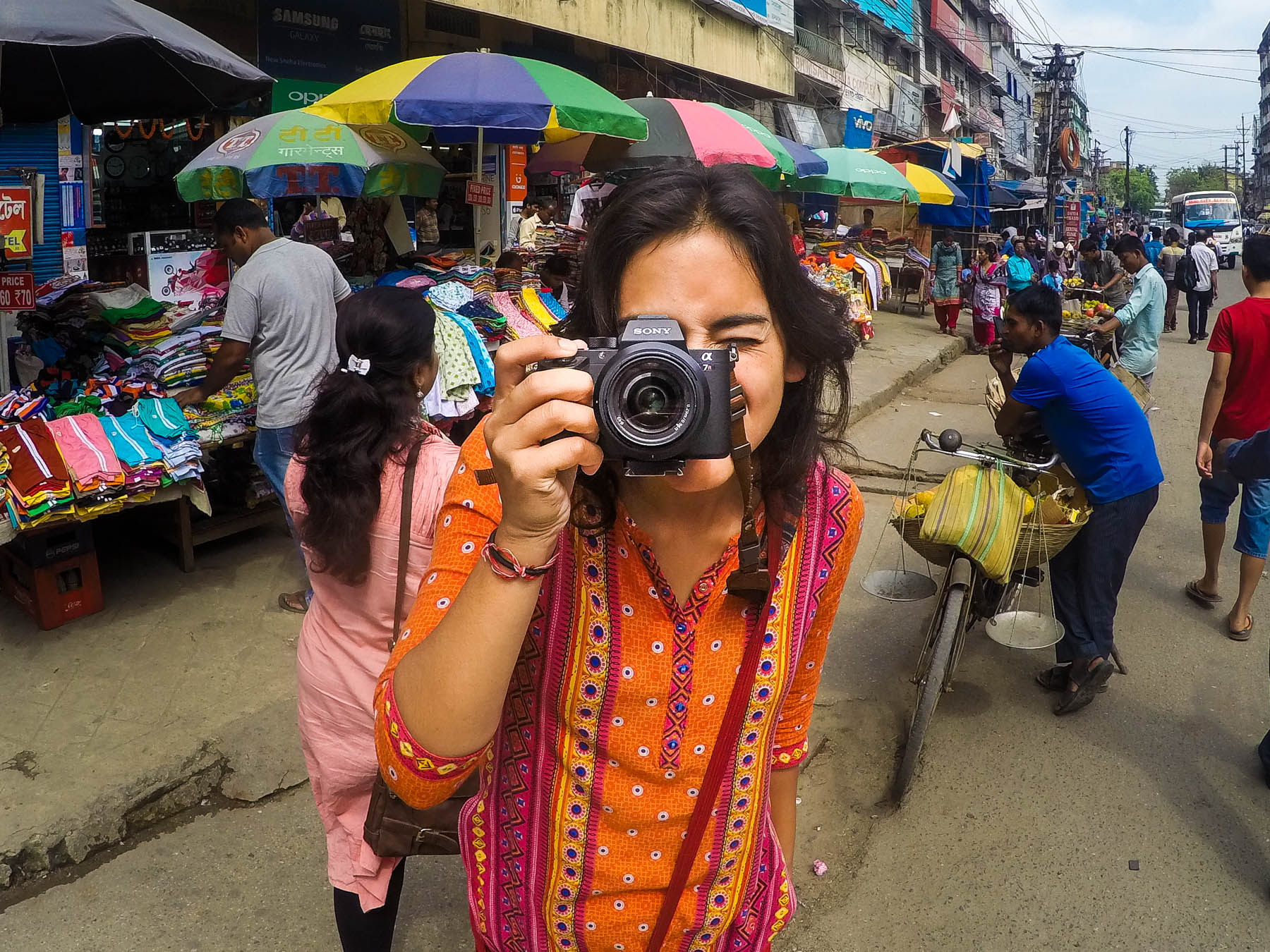 How to upgrade from a Nikon DSLR to a Sony a7RII mirrorless full-frame camera, the best travel camera out there - Alex with a Sony a7RII in a market in Assam, India - Lost With Purpose