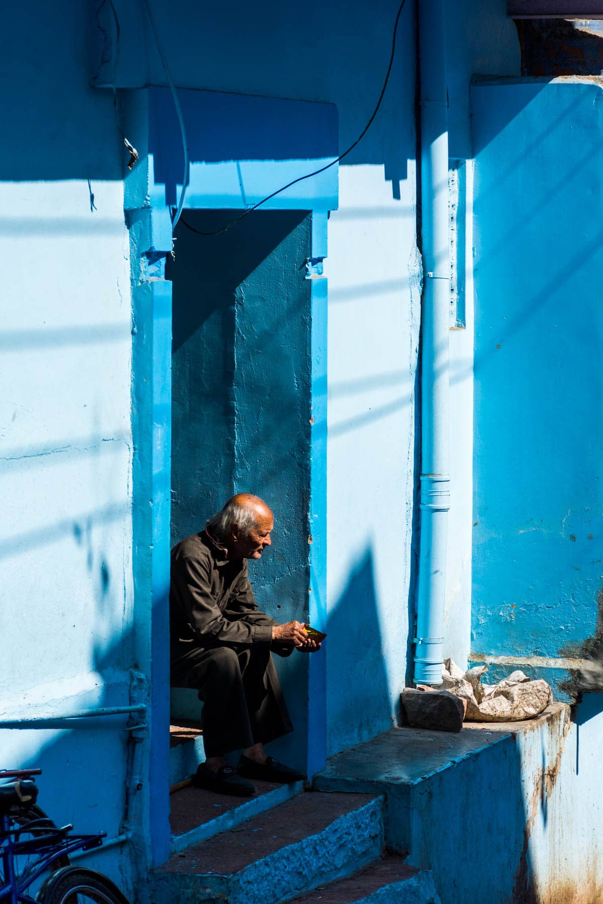 A man sitting on a blue stoop