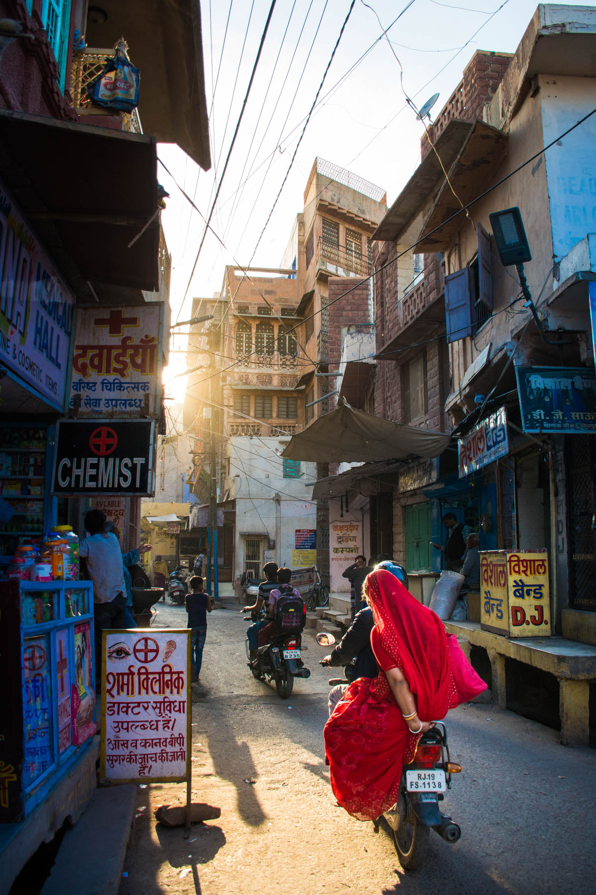 A lady in a red sari zipping past on a motorbike during sunset in Jodhpur, Rajasthan, India.