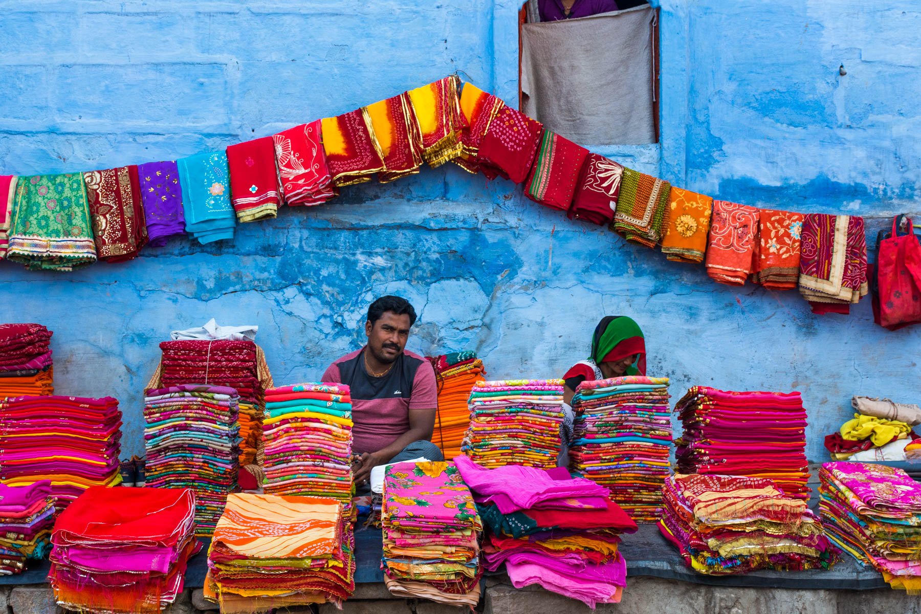 A man selling fabric in front of a blue building