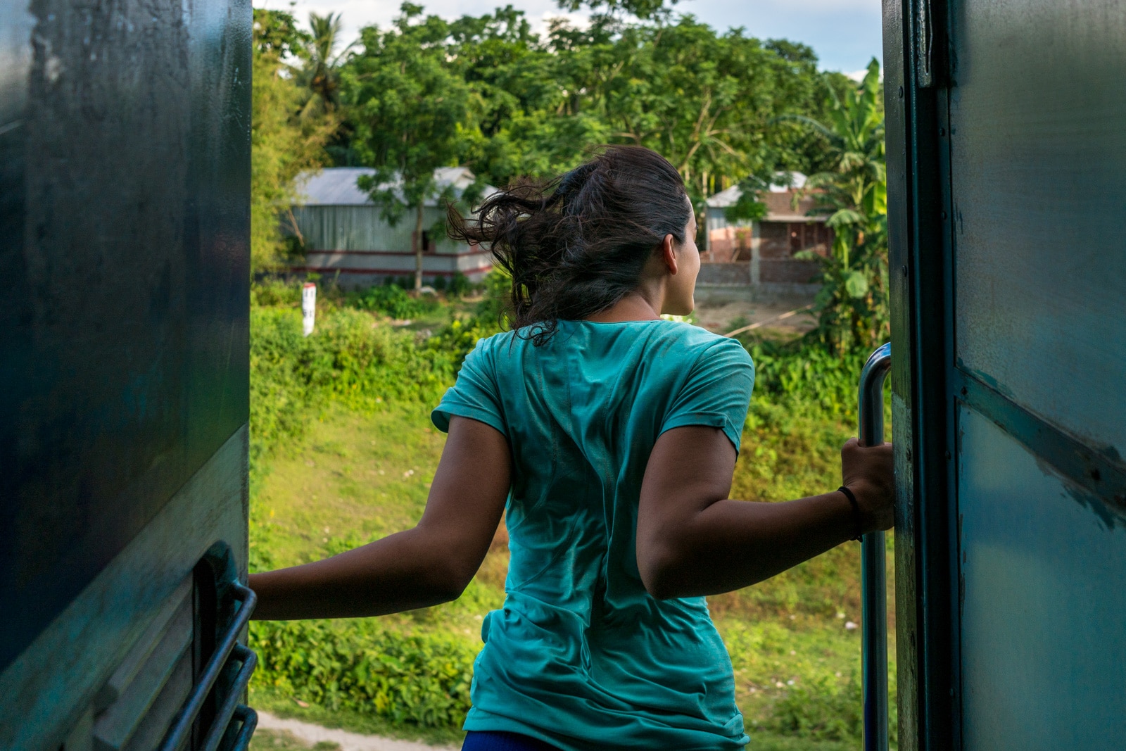 50 ways to deal with excessive sweat while traveling - Alex hanging out of a train in India - Lost With Purpose