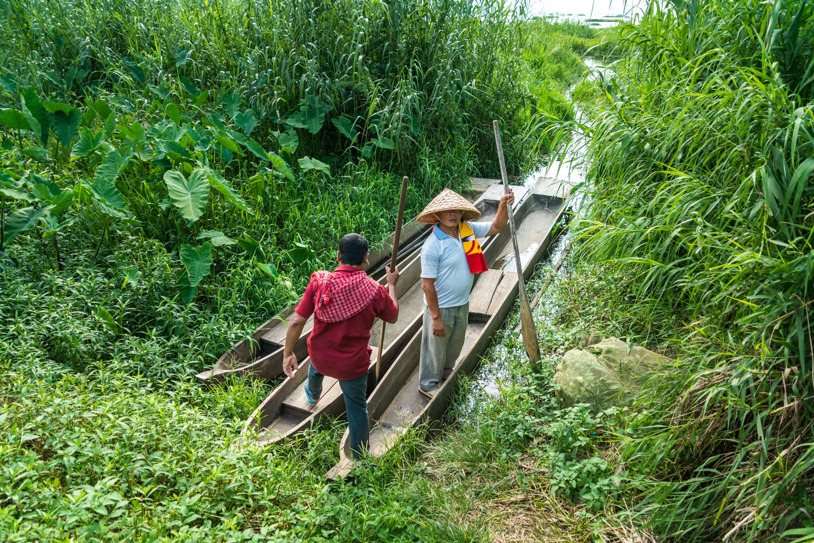 Why you need to visit Loktak Lake, Manipur, Northeast India - Two men climbing into wooden boats - Lost With Purpose