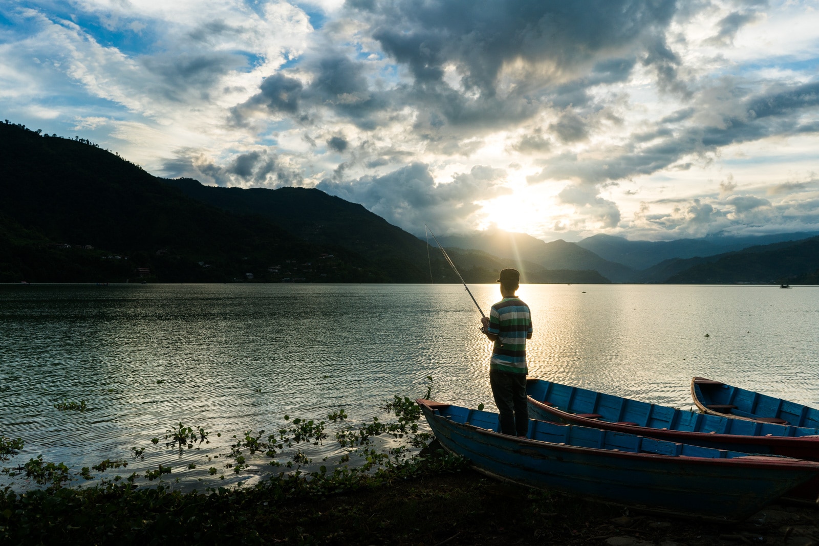 Travel in Nepal during monsoon - A boy fishing at Phewa Lake in Pokhara - Lost With Purpose travel blog