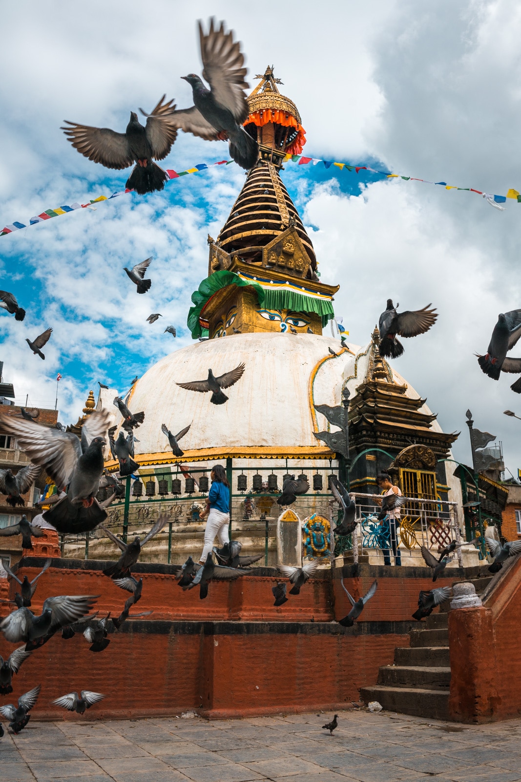 Flocks of birds flying before one of many scenic small stupas found throughout Kathmandu, Nepal.