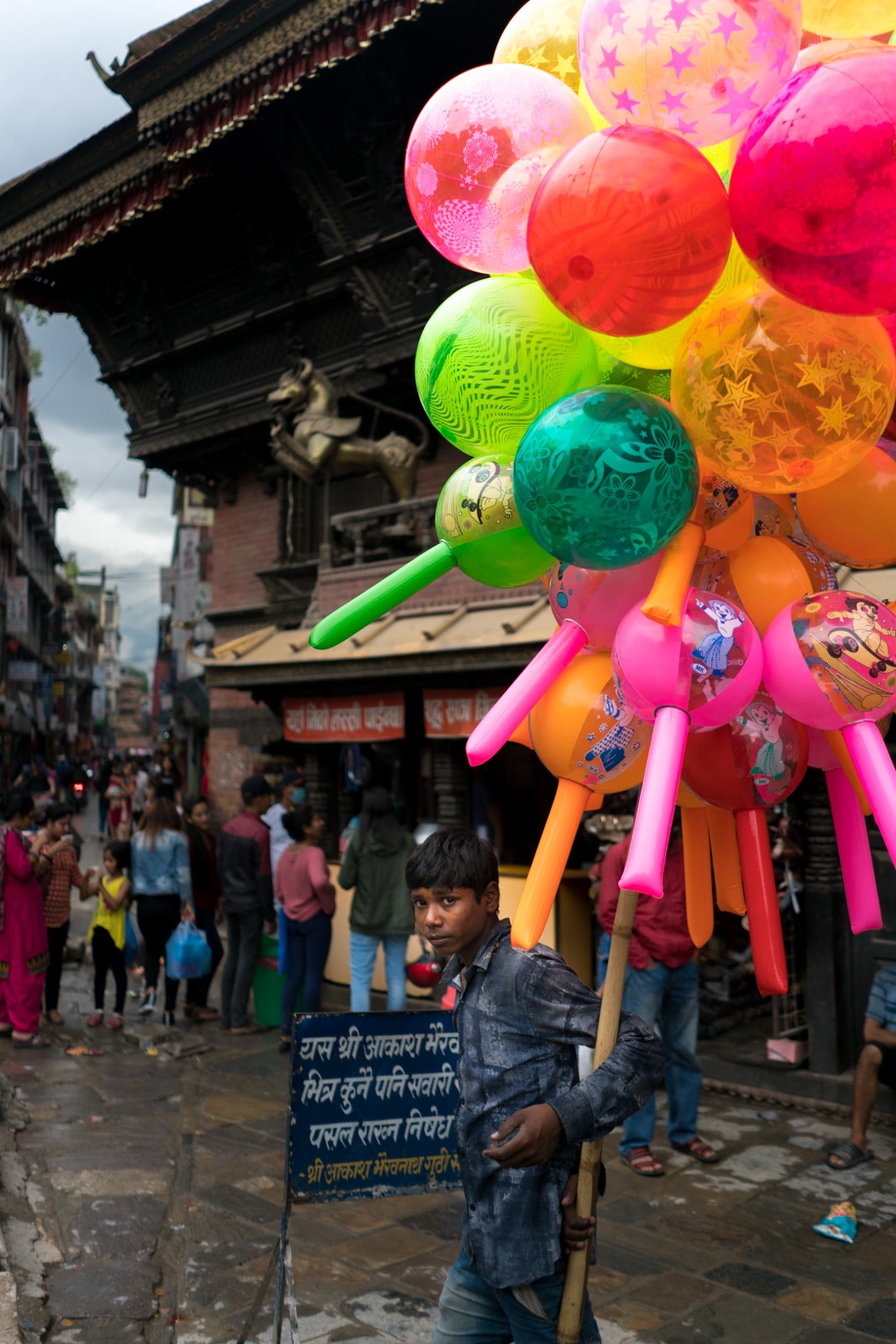 A young boy selling colorful balloons in a street market in Kathmandu, Nepal.