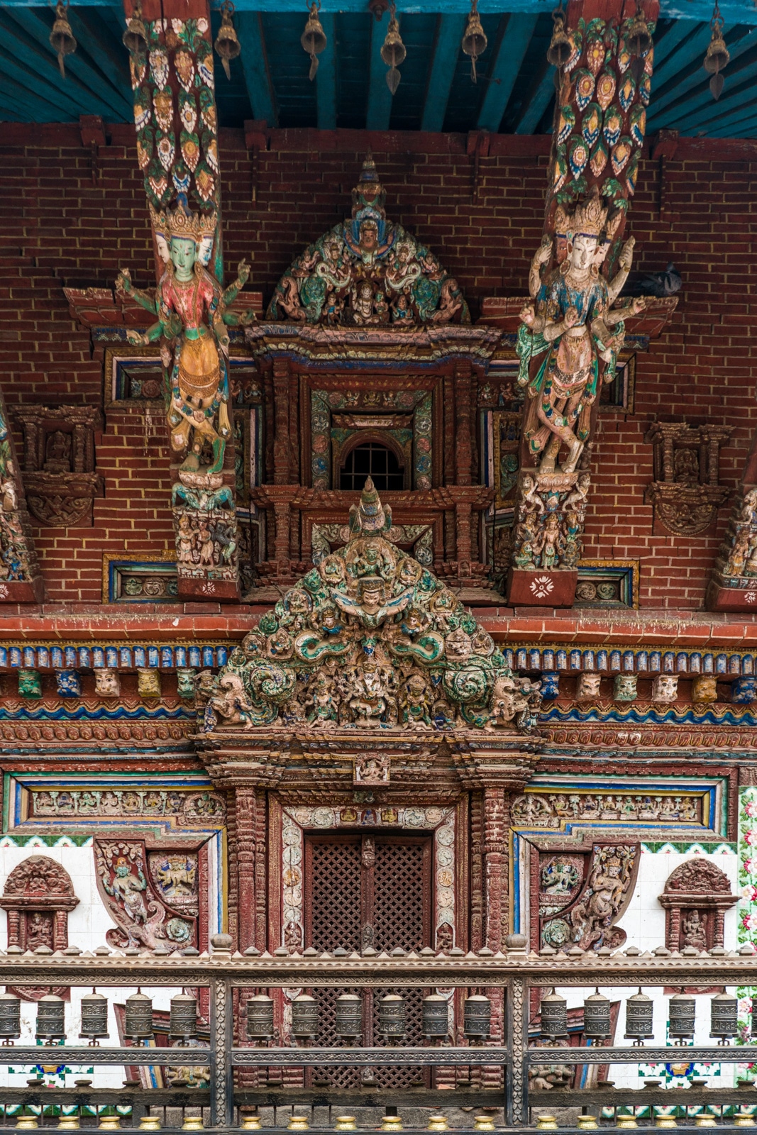 Intricate, painted wooden detail work on a red brick Buddhist stupa in the center of Patan, Nepal.