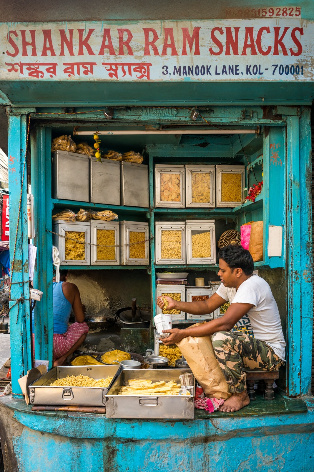 A tiny blue hole-in-the-wall fried snack stand in Kolkata, West Bengal, India.
