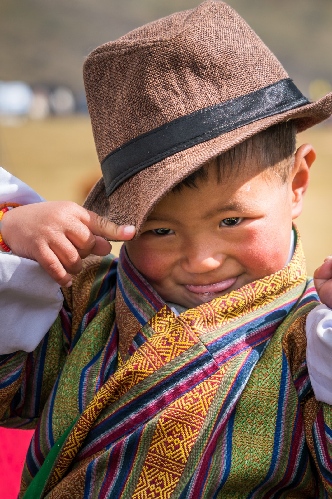 An adorable young Bhutanese boy rocking a fedora and colorful "gho", traditional male Bhutanese dress, at the 2017 Royal Highlander Festival in Laya, Bhutan.