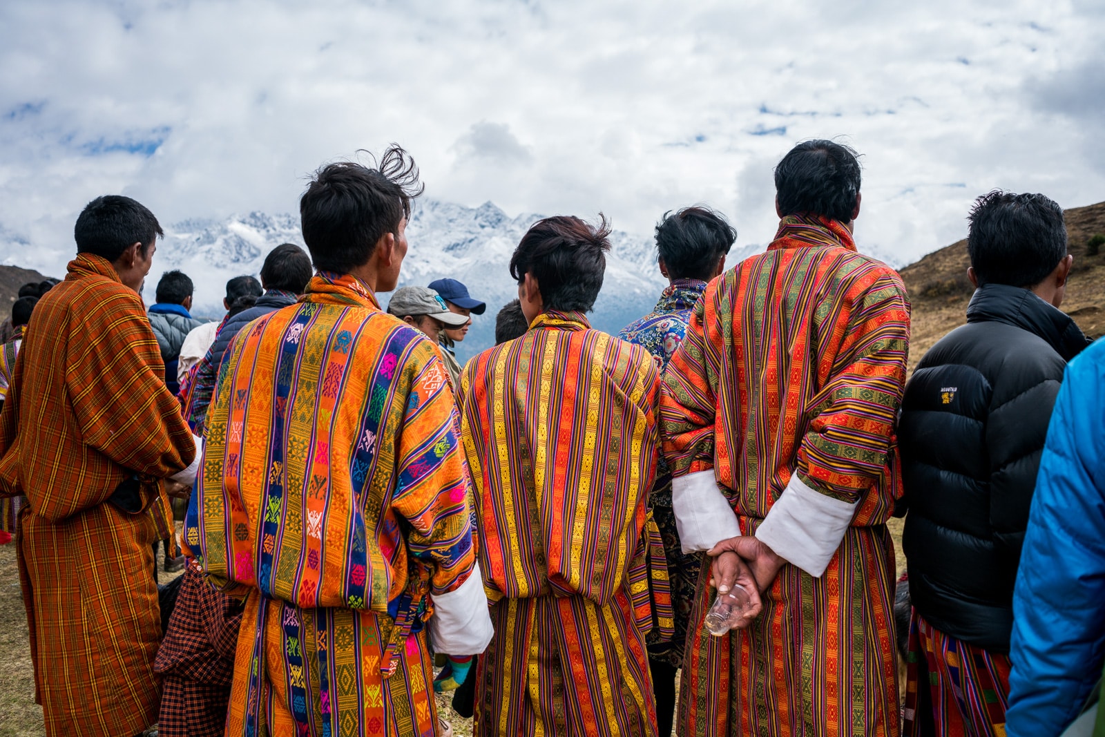 Photos of the 2017 Royal Highlander Festival in Bhutan - Men in colorful traditional Bhutanese gho watching the spectacle - Lost With Purpose travel blog