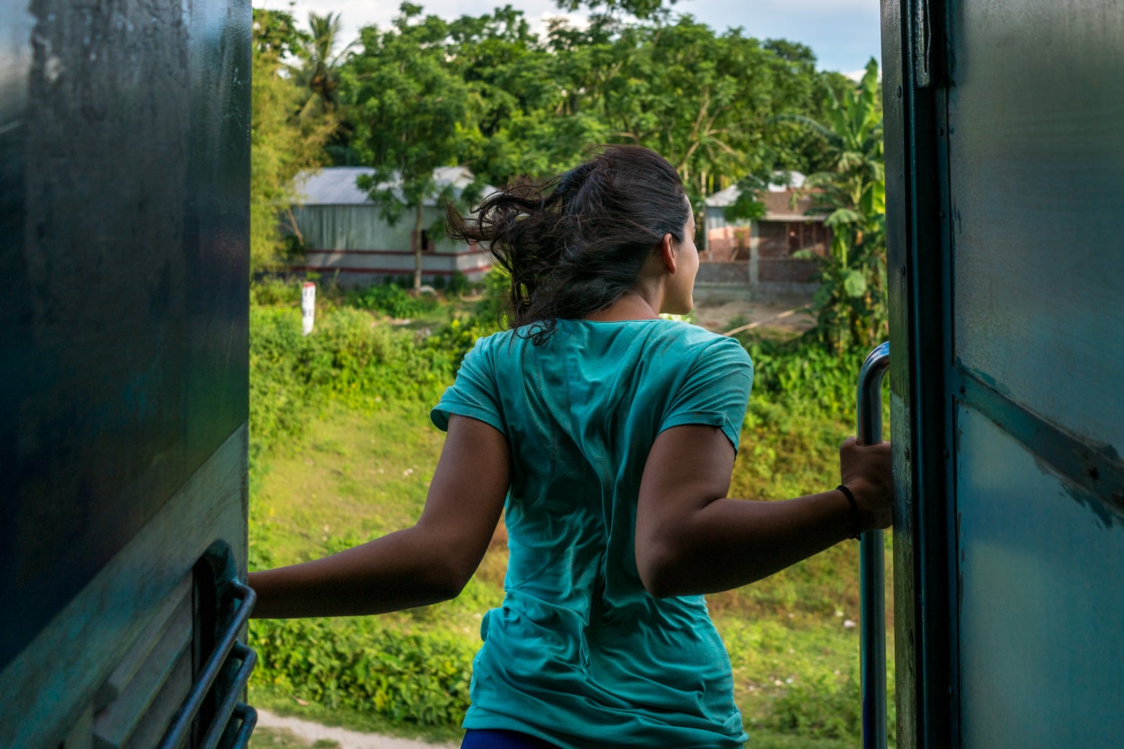 Important things to have in your travel insurance - Alex hanging out of train in India - Lost With Purpose travel blog