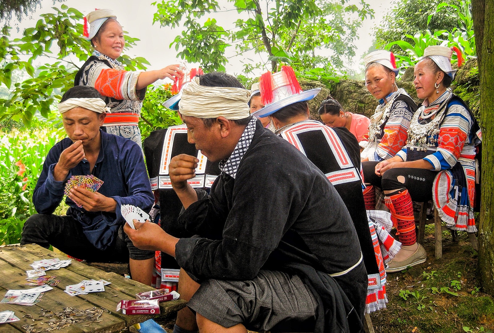 Exploring off the beaten track villages in Guizhou, China - Geija locals in traditional dress eating sunflower seeds