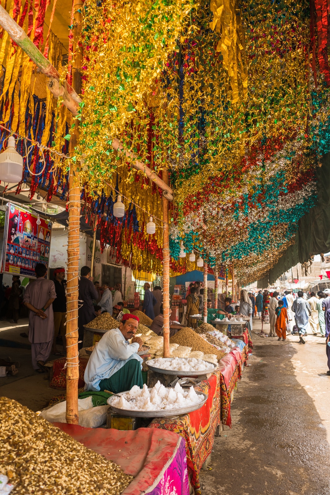 Man selling snacks on the streetside at the Urs of Lal Shahbaz Qalandar in Sehwan Sharif, Pakistan.