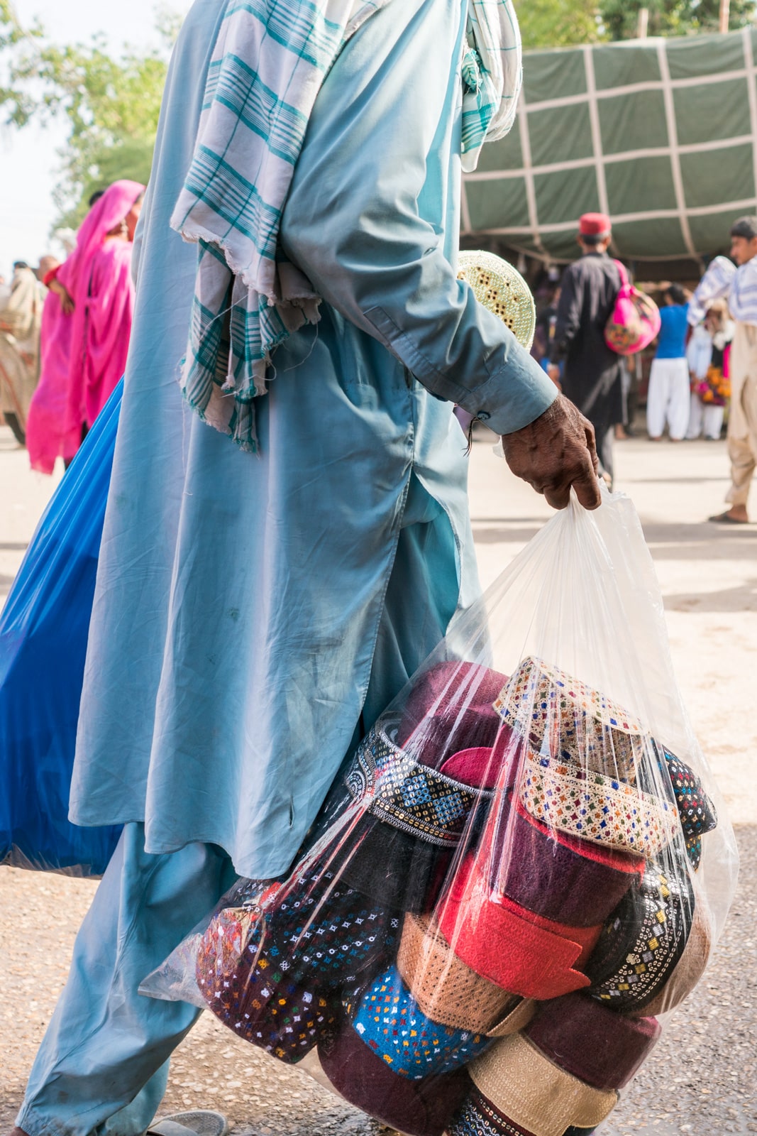 A man carrying a bag of Sindhi hats at the Urs of Lal Shahbaz Qalandar in Sehwan, Pakistan.