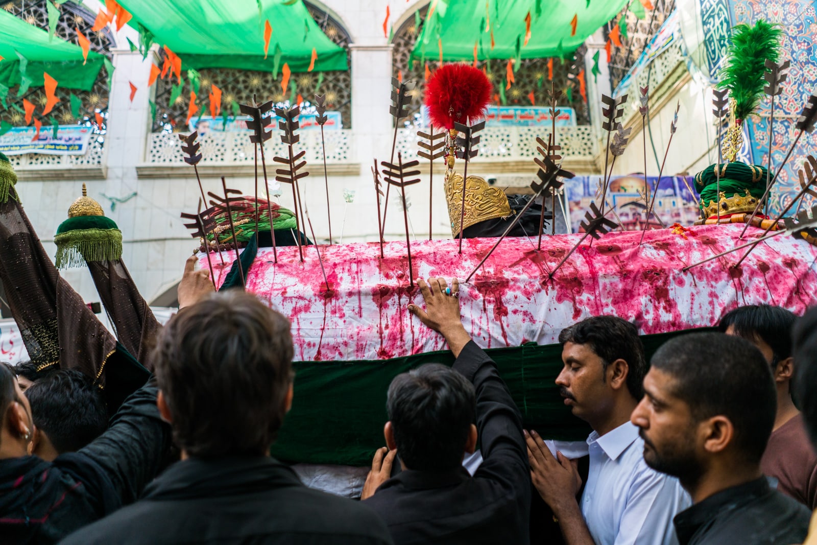 The Urs of Lal Shahbaz Qalandar in Sehwan, Pakistan - Man touching Shia coffin with blood and arrows outside the shrine - Lost With Purpose travel blog