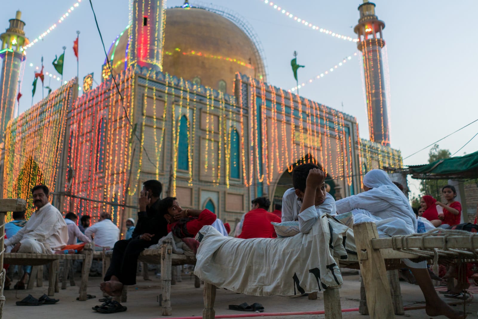 The Urs of Lal Shahbaz Qalandar in Sehwan, Pakistan - Boy lounging on charpoy bed near shrine - Lost With Purpose travel blog