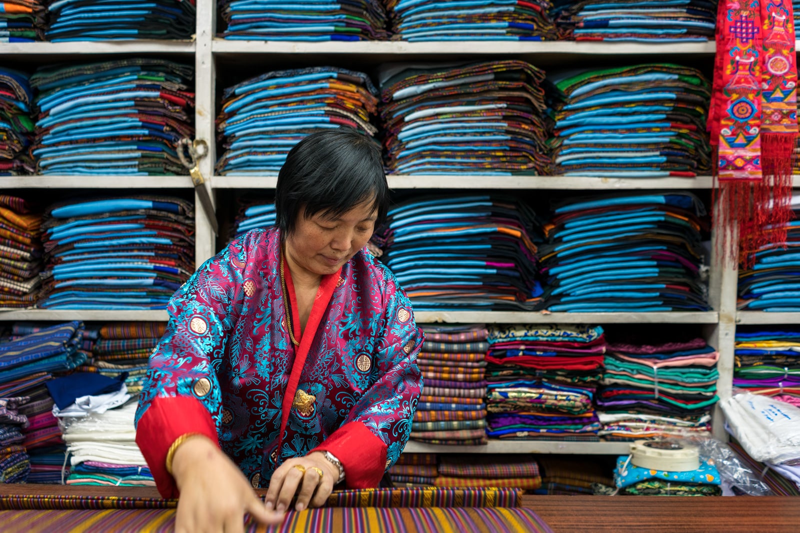 Photos of Bhutan - Woman folding traditional fabric for gho in Thimphu - Lost With Purpose travel blog