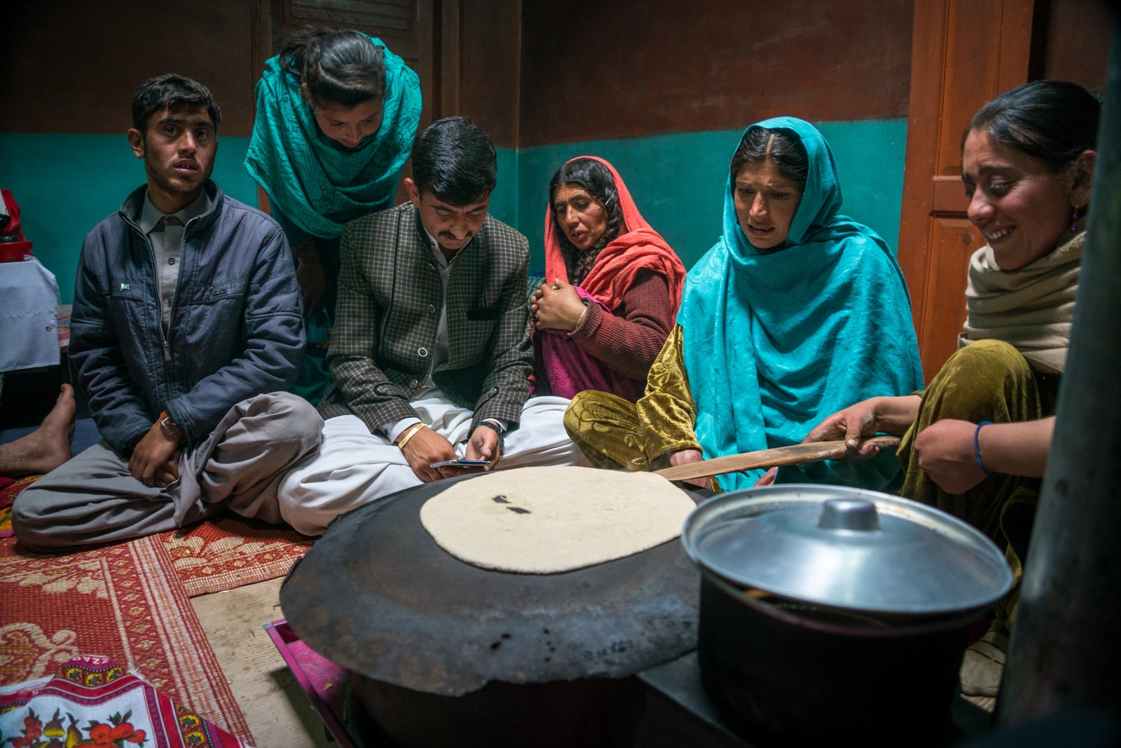 Phander Valley travel guide - Family in a traditional house with bread cooking on the stove - Lost With Purpose travel blog