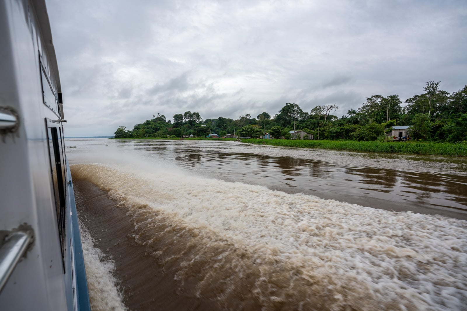 Taking the fast boat from Manaus, Brazil to Leticia, Colombia - Exterior of the fast boat and views of riverside Amazonian houses - Lost With Purpose travel blog