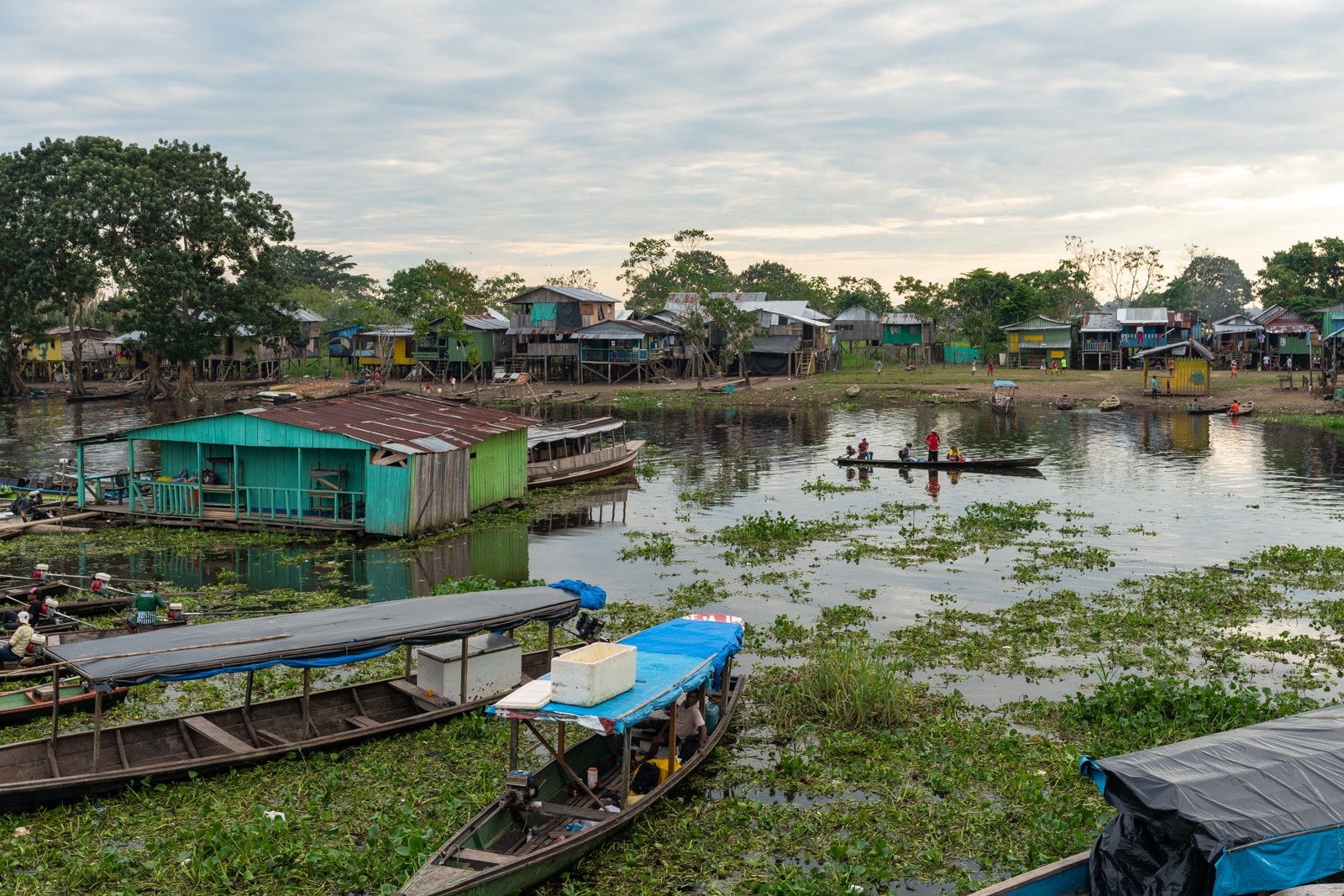 Taking the fast boat from Manaus, Brazil to Leticia, Colombia - Leticia canal at sunset with houses and people - Lost With Purpose travel blog