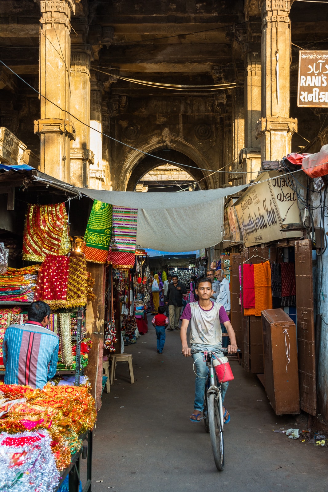 A young Indian boy riding a bicycle through a market street in Ahmedabad