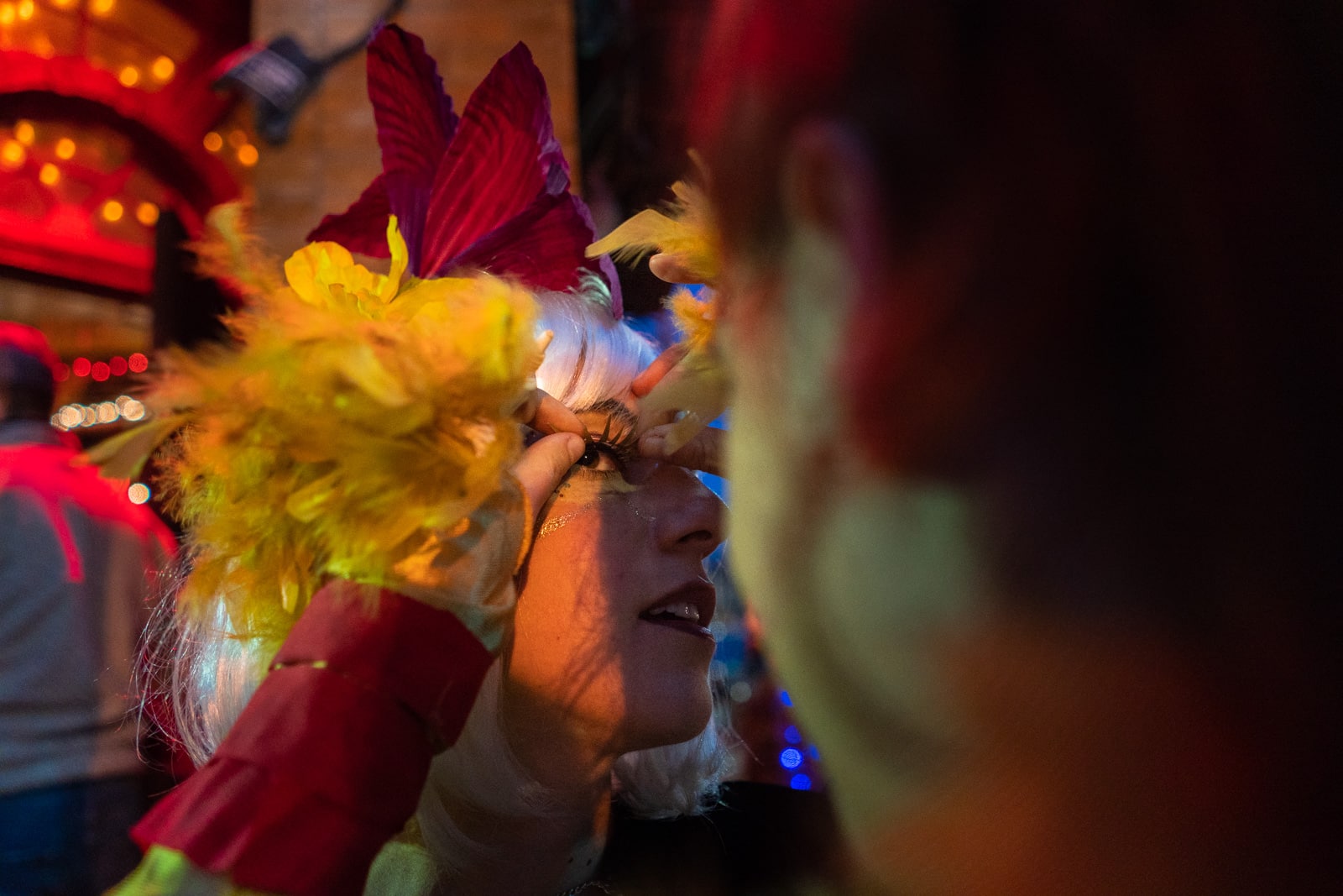 Gluing fake eyelashes onto a girl for a Mardi Gras parade in New Orleans