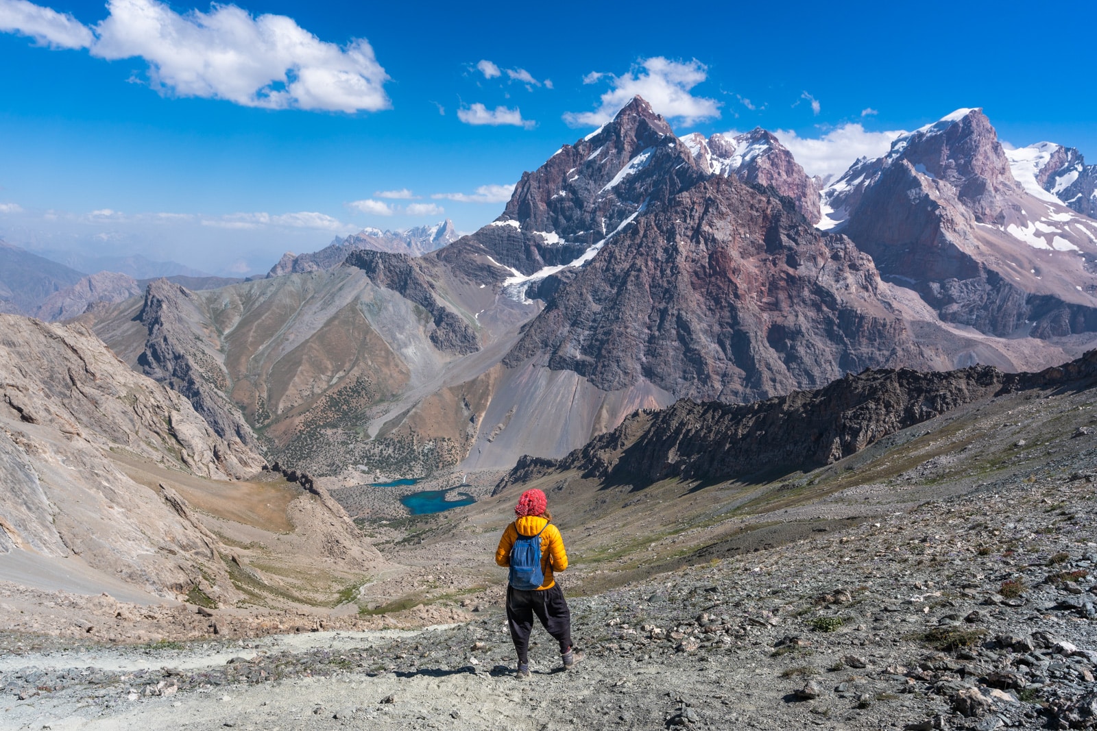 Trekker standing on Alauddin Pass overlooking Alauddin Lake in Tajikistan's Fann Mountains