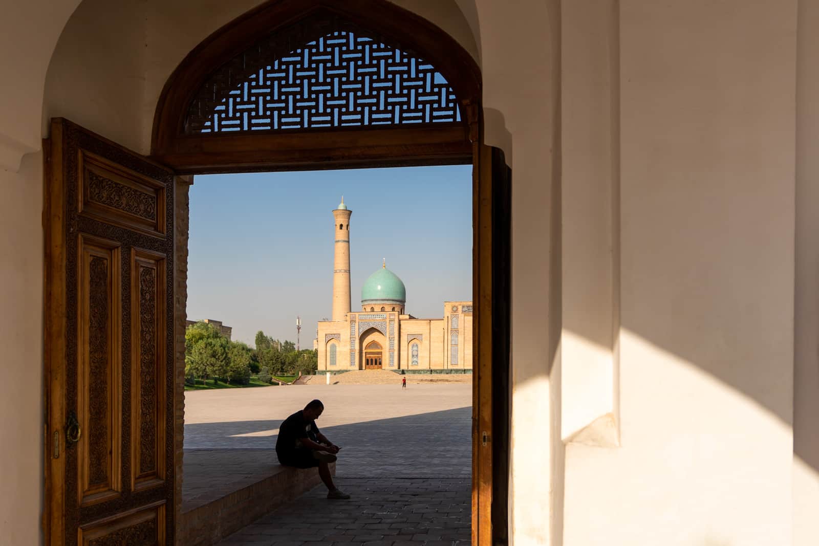 A man sitting in shadow in the Khast Imam complex in