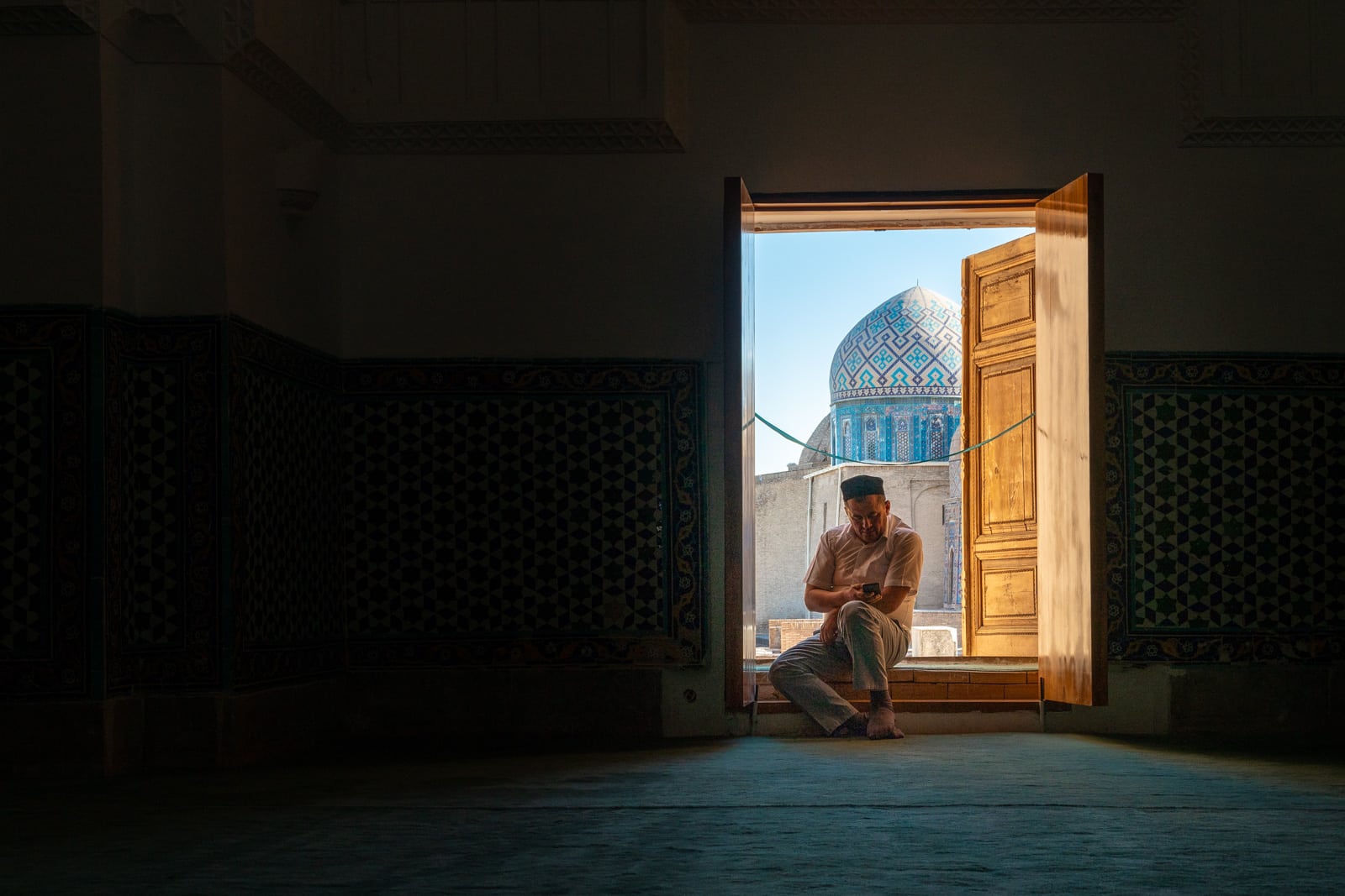 A man checking his phone in the Shah-i-Zinda necropolis in Samarkand, Uzbekistan