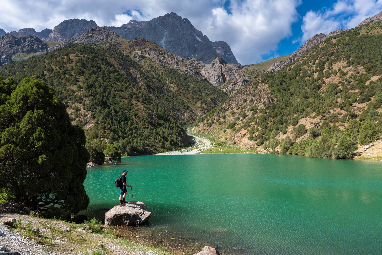 Trekker by a lake in Tajikistan's Fann Mountains