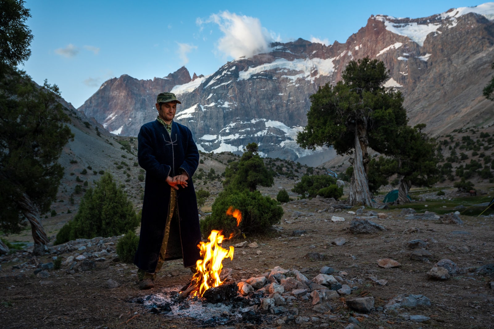 Porter warming himself by the fire in Tajikistan's Fann Mountains at sunrise