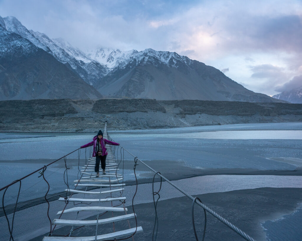 Woman walking across the Passu suspension bridge in Pakistan