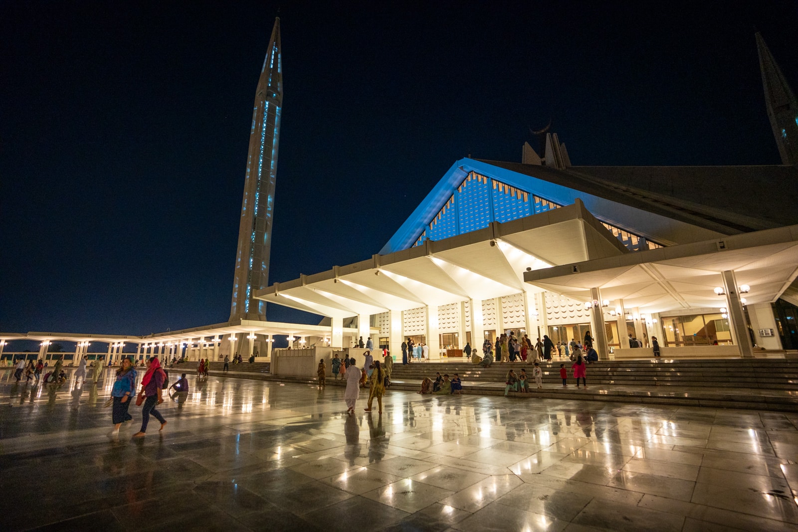 Night time view of people walking around Faisal Mosque in Islamabad