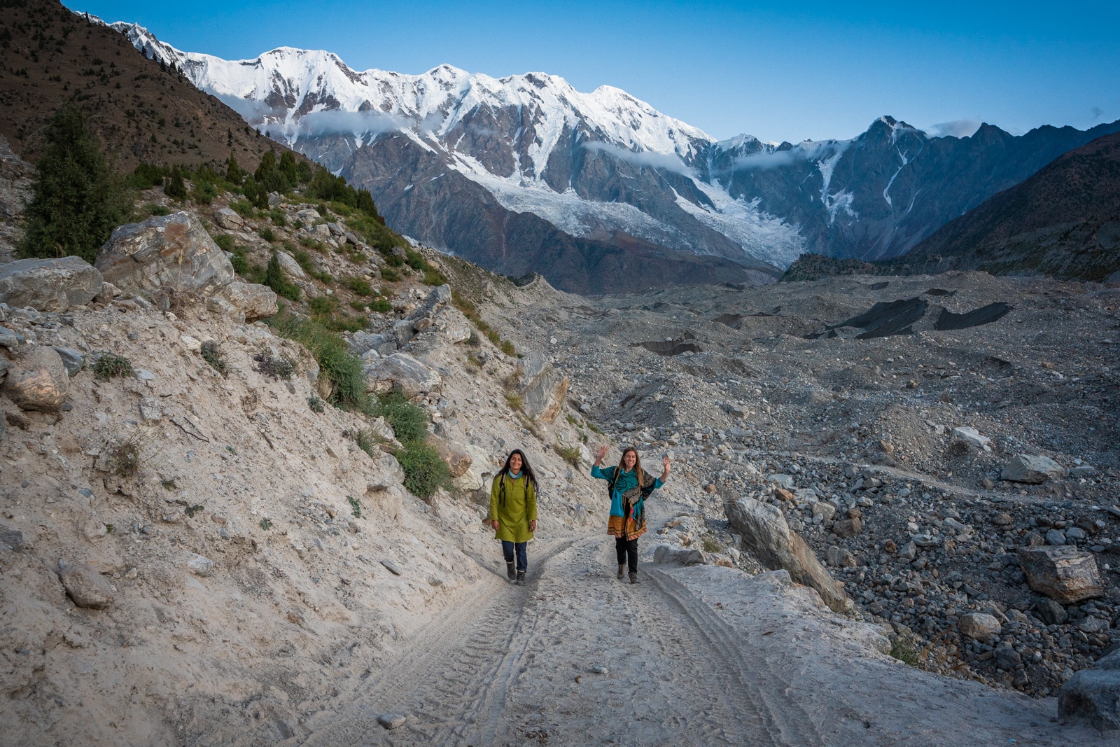 Female travelers walking on a dirt jeep track through Tarashing, Astore, Pakistan