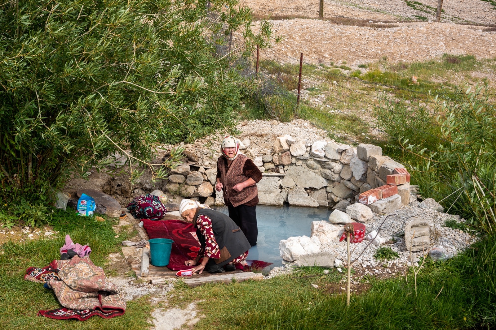 Women washing clothes in a fish pond in Shaimak Village, Pamir Mountains, Tajikistan