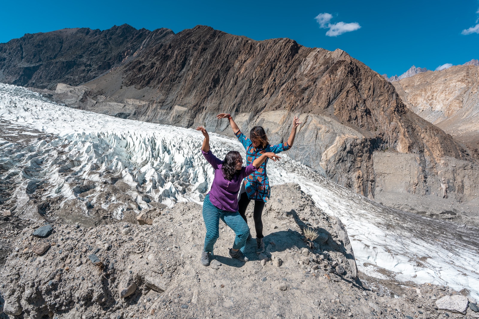 Two female travelers dancing near Passu glacier