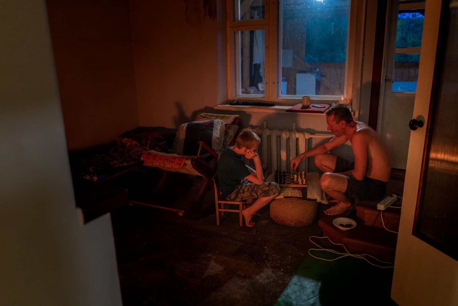 Father and son playing chess by a fire in Siberia, Russia