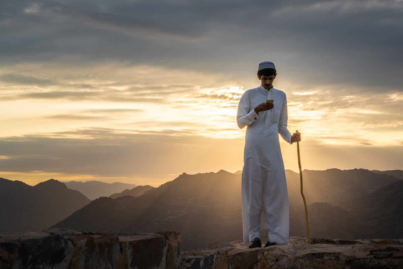 Boy using his mobile phone during sunset in Najran, Saudi Arabia