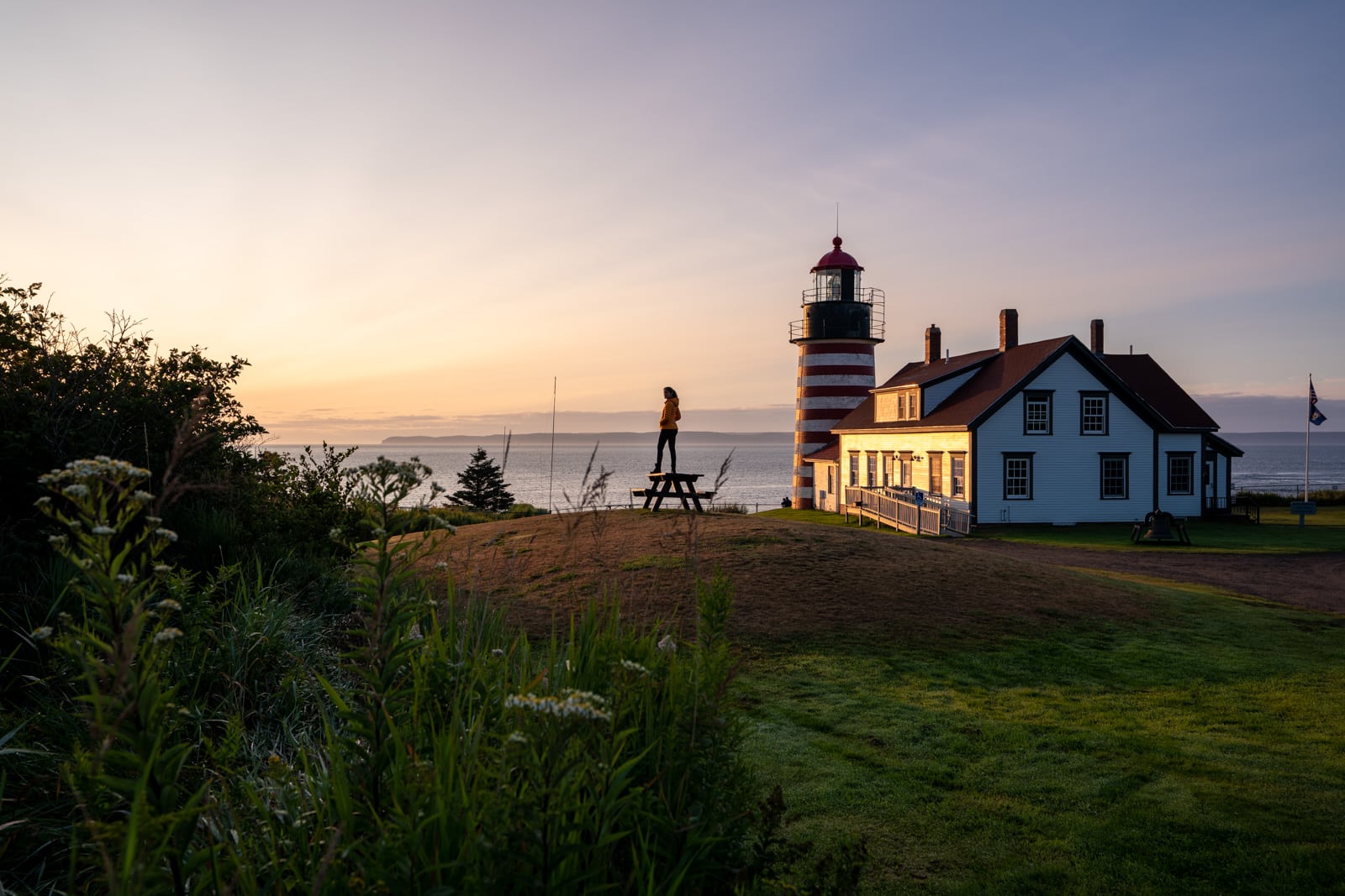 Female traveler watching sunrise in West Quoddy Head, Maine, United States of America