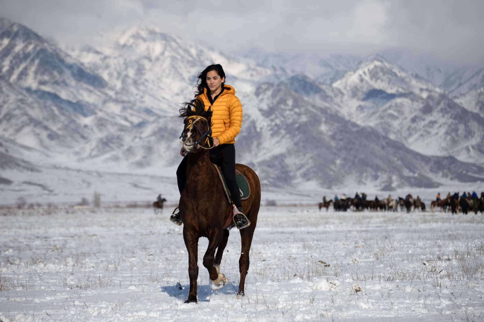 Female traveler riding a horse in Kyrgyzstan in winter