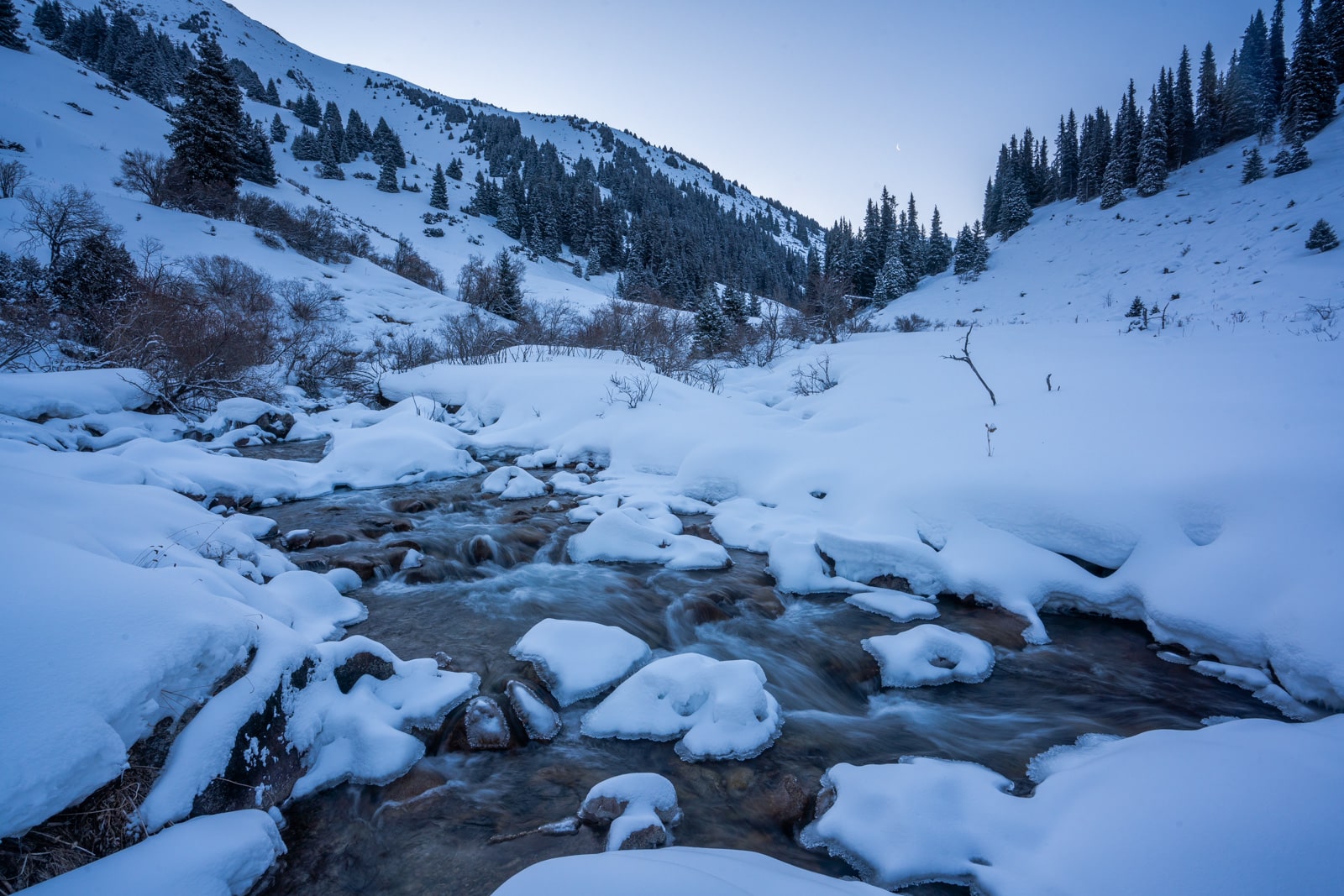 A stream in Boz Uchuk, Kyrgyzstan in winter surrounded by snow